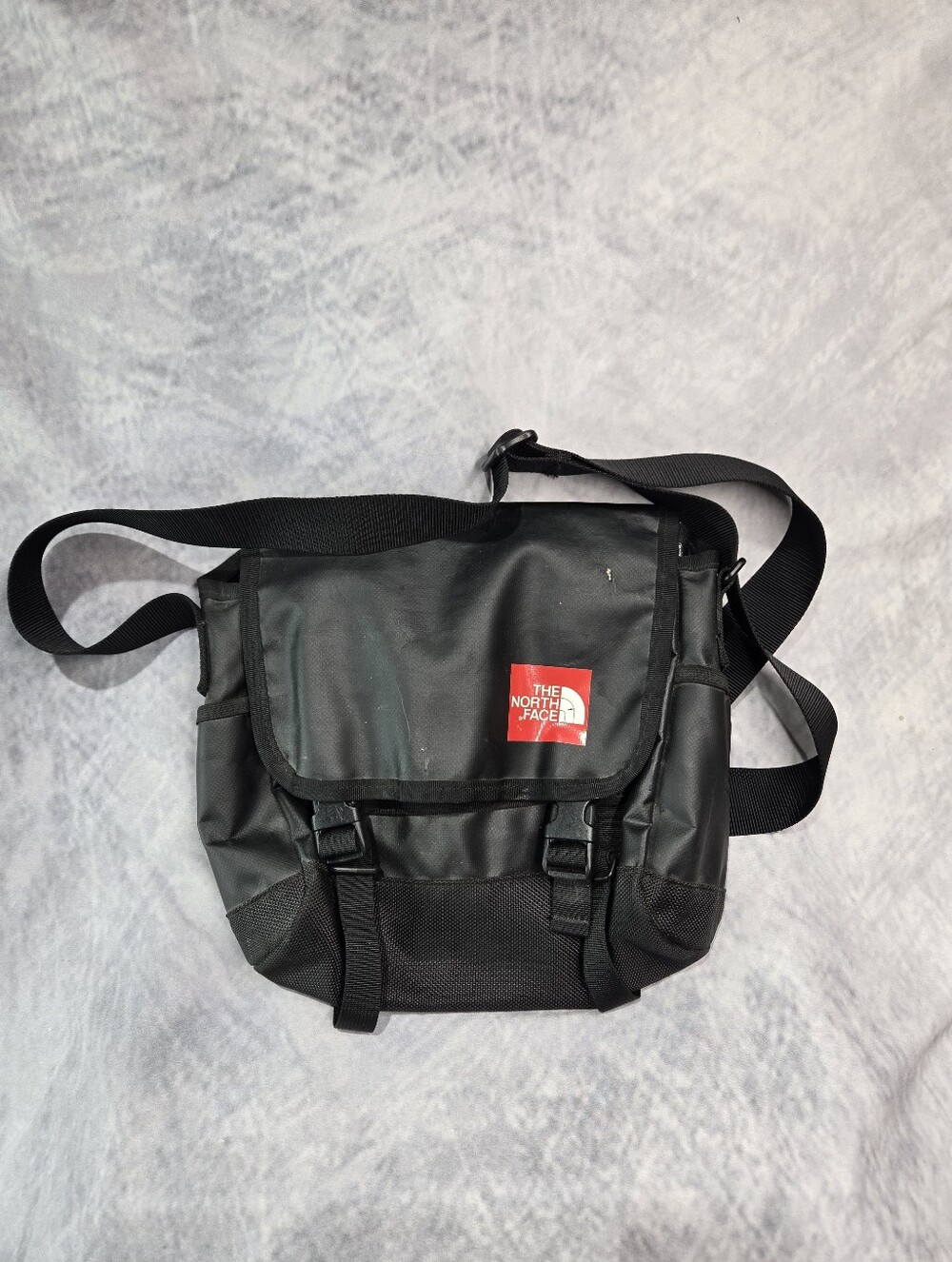 The North Face''s black messenger bag made of water-resistant material.
